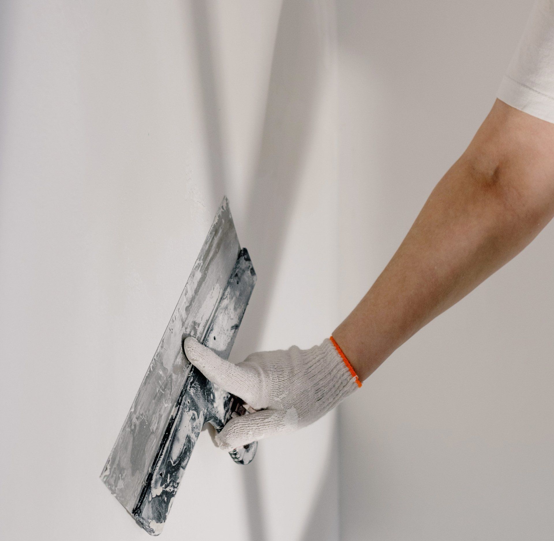 A person is painting a wall blue with a paint roller