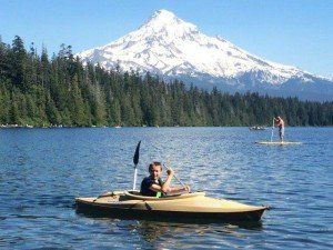 Kayaker on lake at foot of snowy mountain