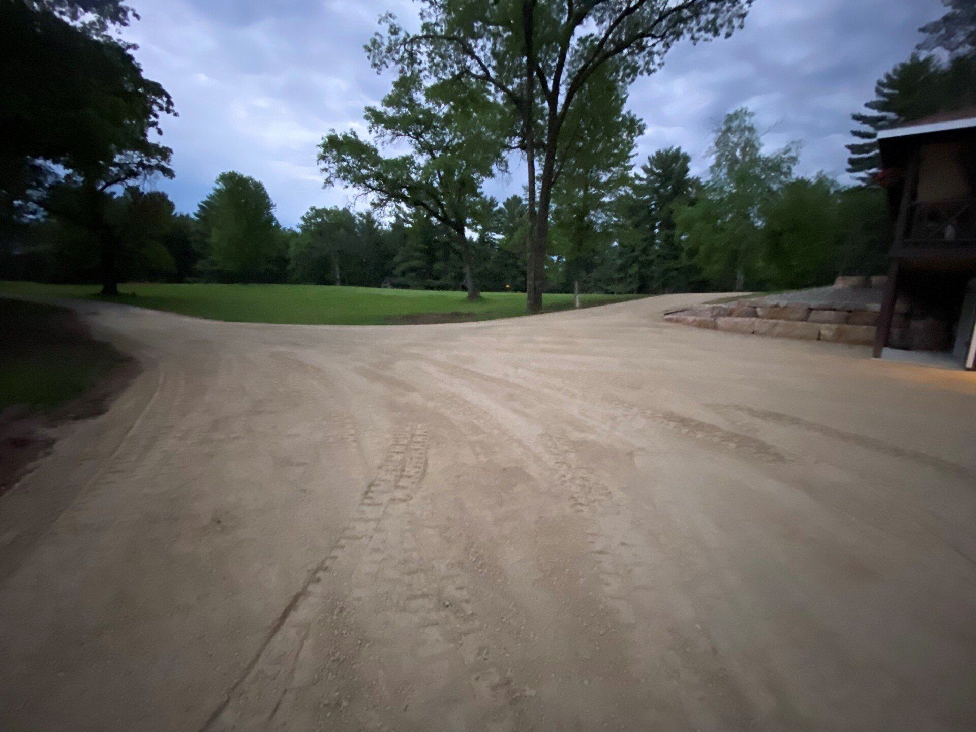 Gravel driveway leading to a grassy yard with trees