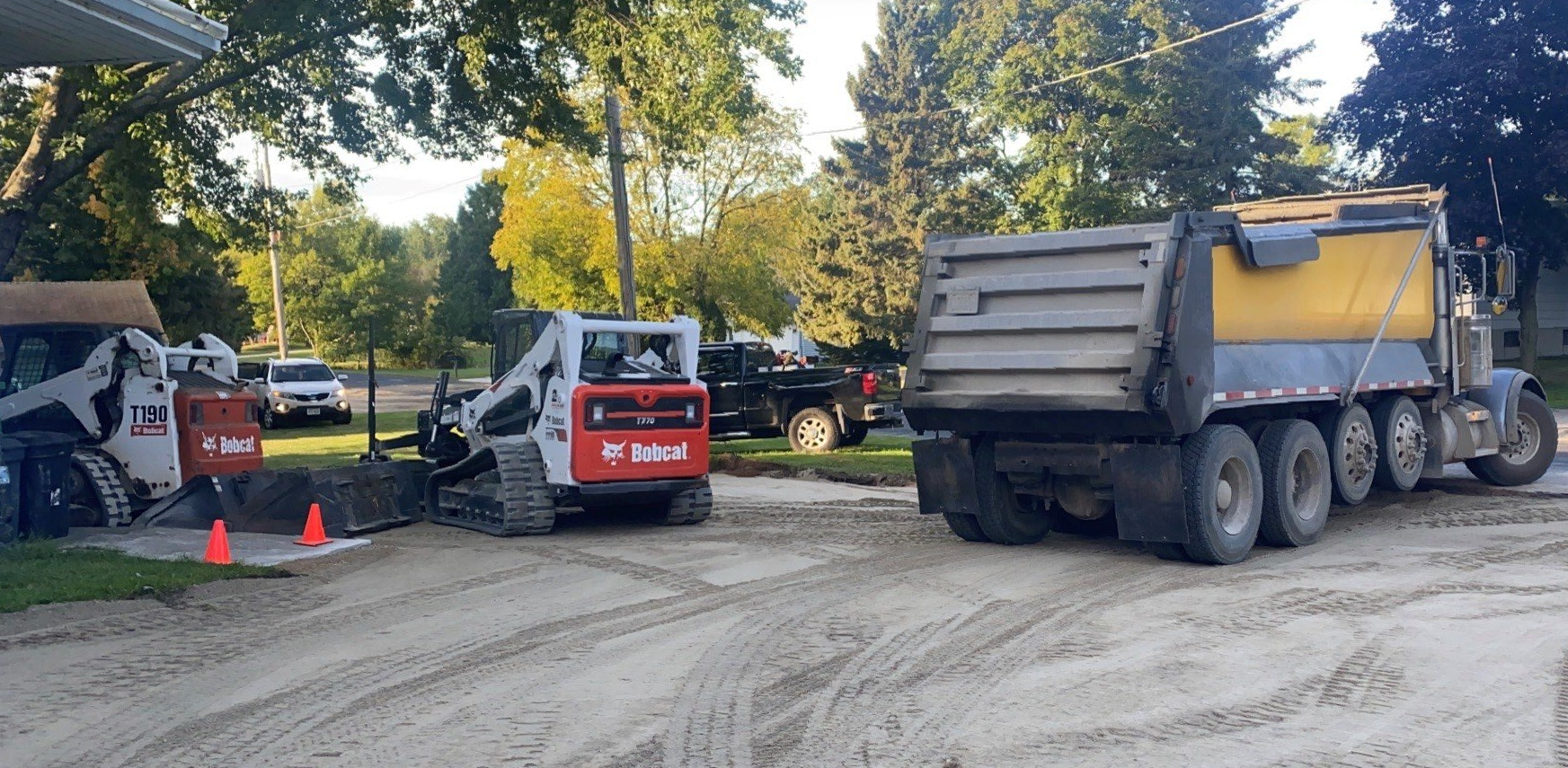 Construction site with a dump truck and two Bobcat skid-steer loaders