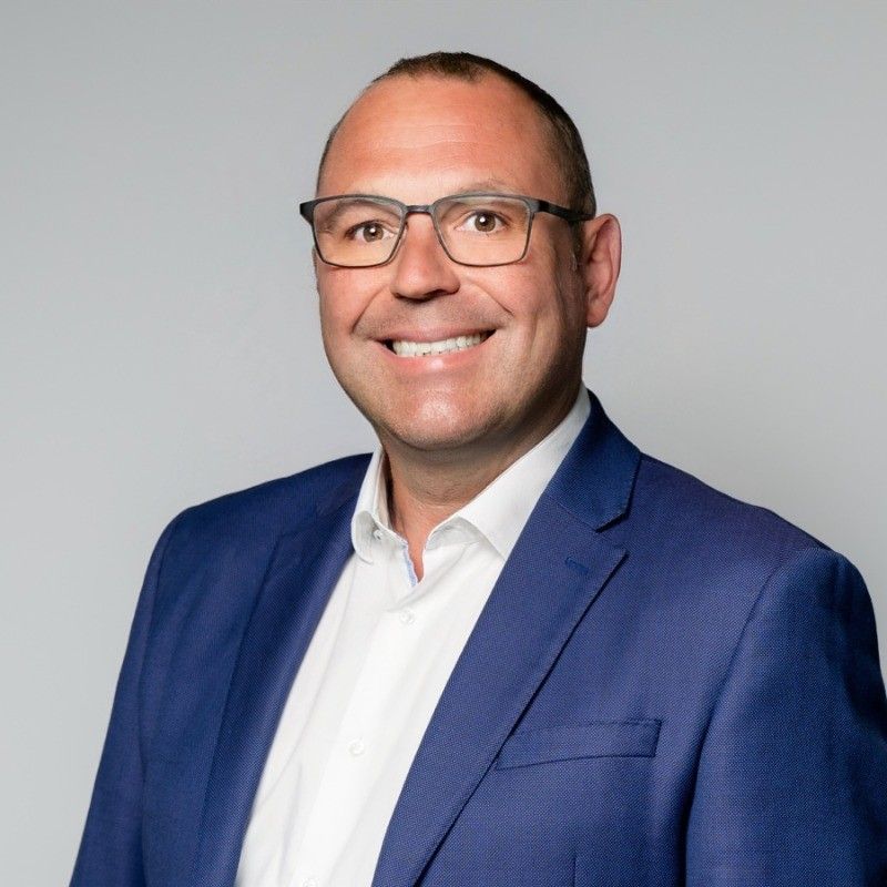 A middle-aged man with a slightly sunburnt face in a light blue shirt, looking directly at the camera.