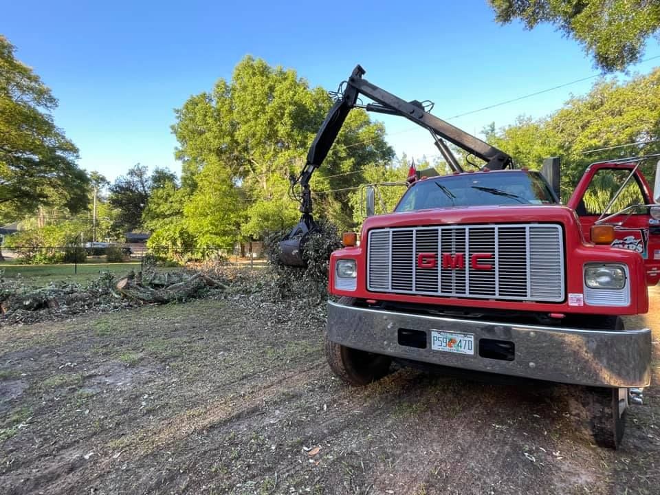 A red gmc truck with a crane attached to the front is driving down a dirt road.