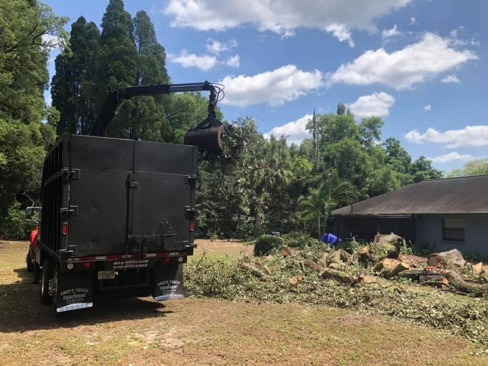 A dump truck with a crane attached to the back of it is parked in front of a house.