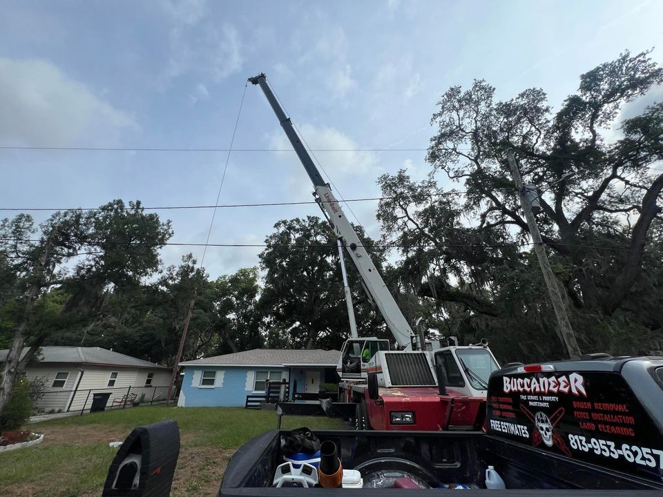 A crane is sitting in the back of a truck in front of a house.