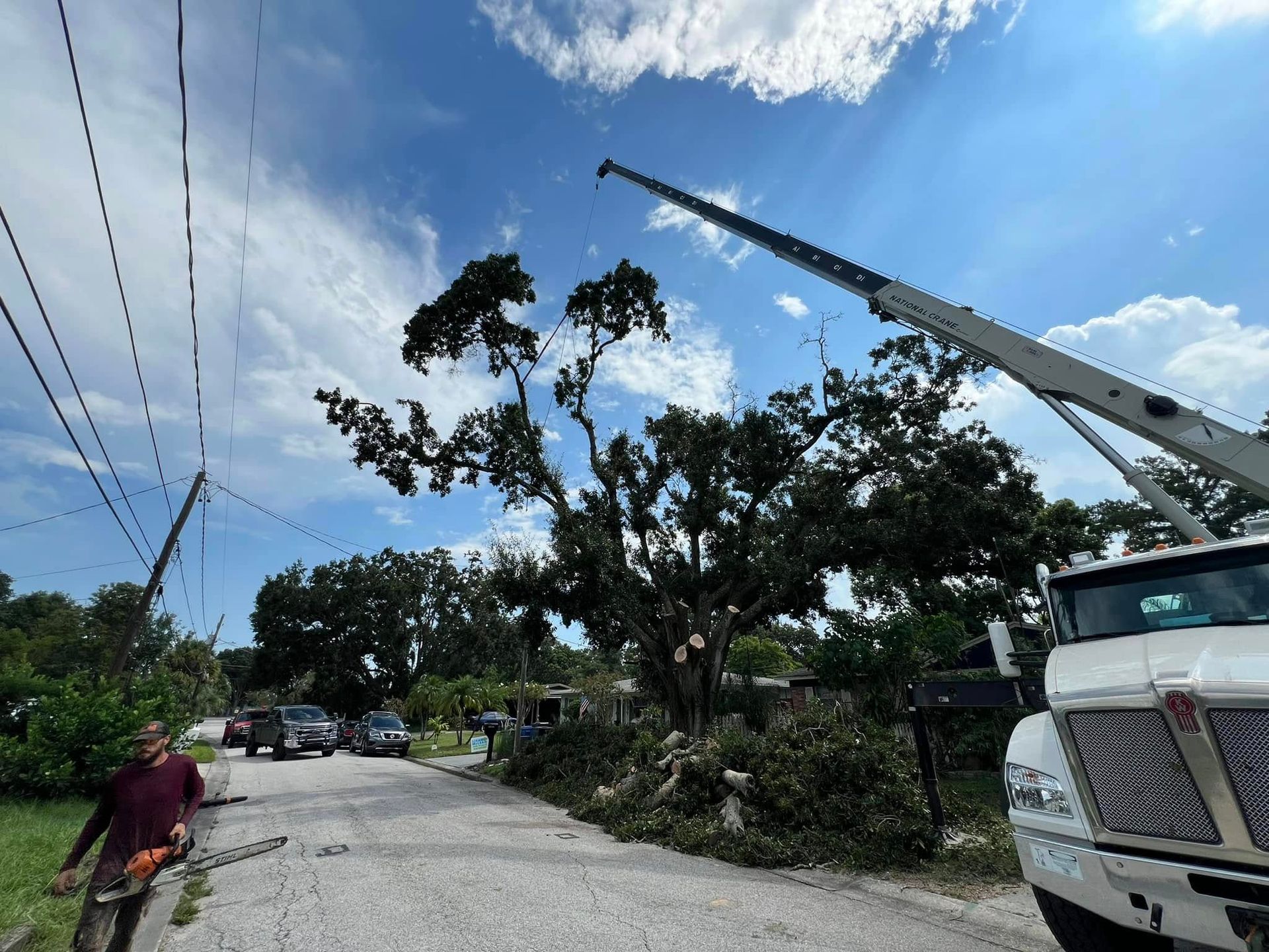 A man is walking down a street next to a truck with a crane attached to it.