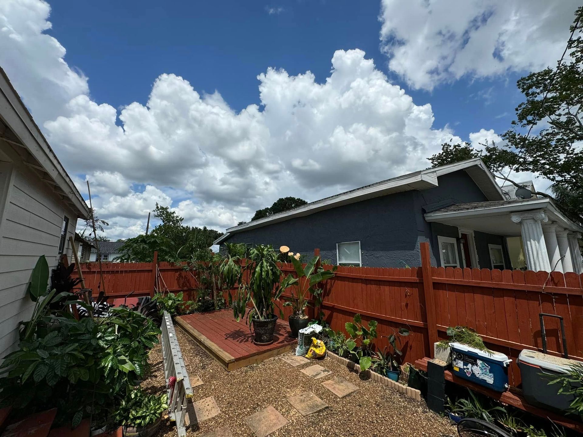 A backyard with a red fence and a house in the background