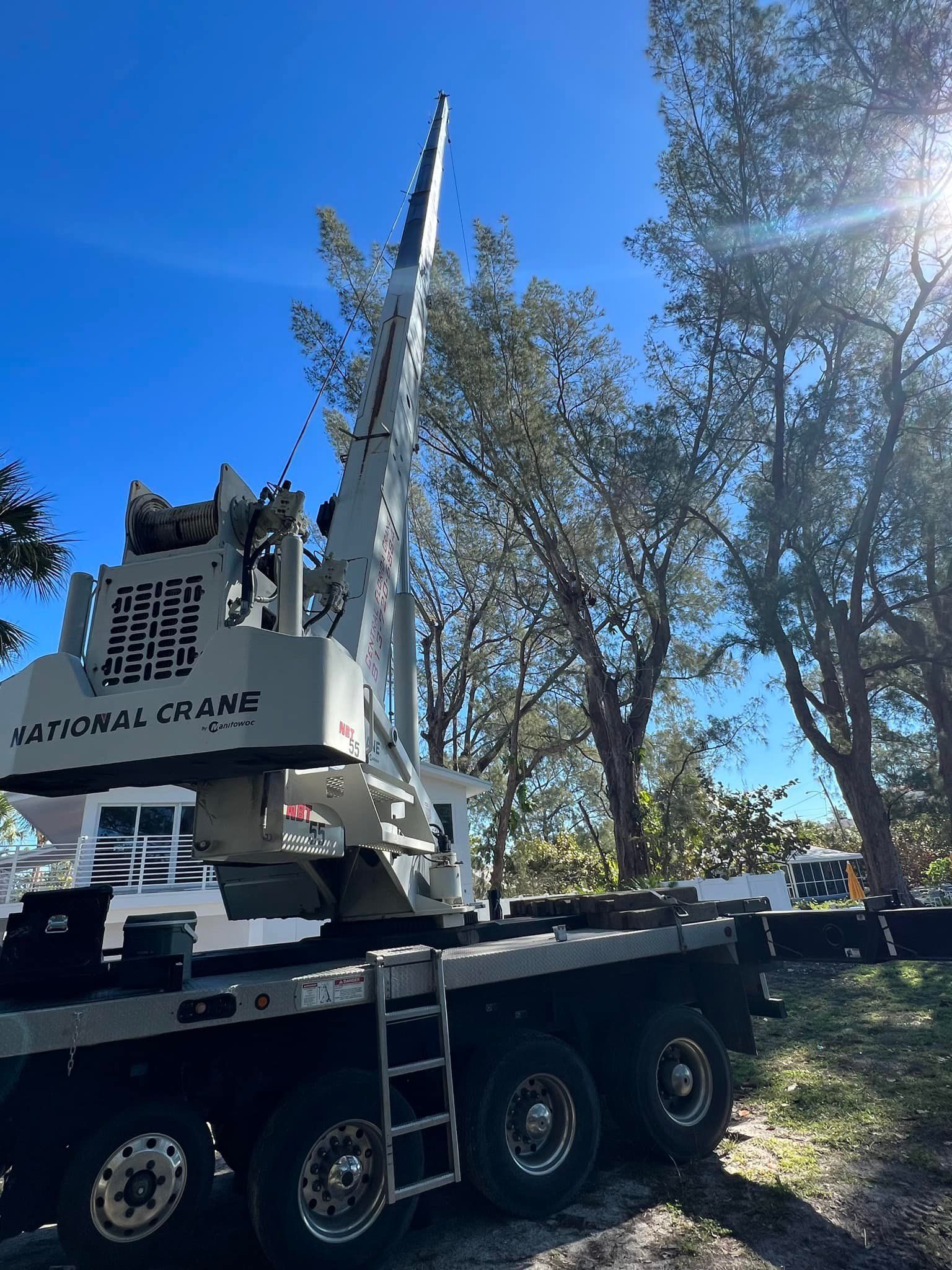 A large truck with a crane on top of it is parked in front of trees.