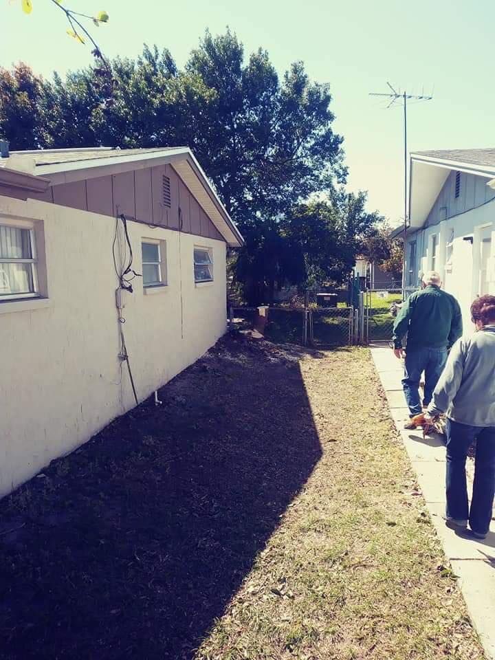 Two people walking down a sidewalk in front of a house