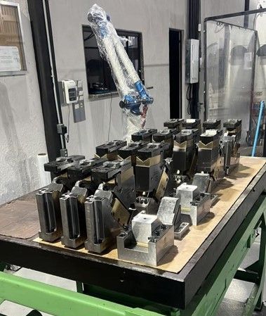 Um braço robótico está sobre uma mesa com um monte de pedaços de metal sobre ele.