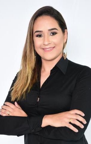 Uma mulher de camisa preta está posando para uma foto com os braços cruzados.