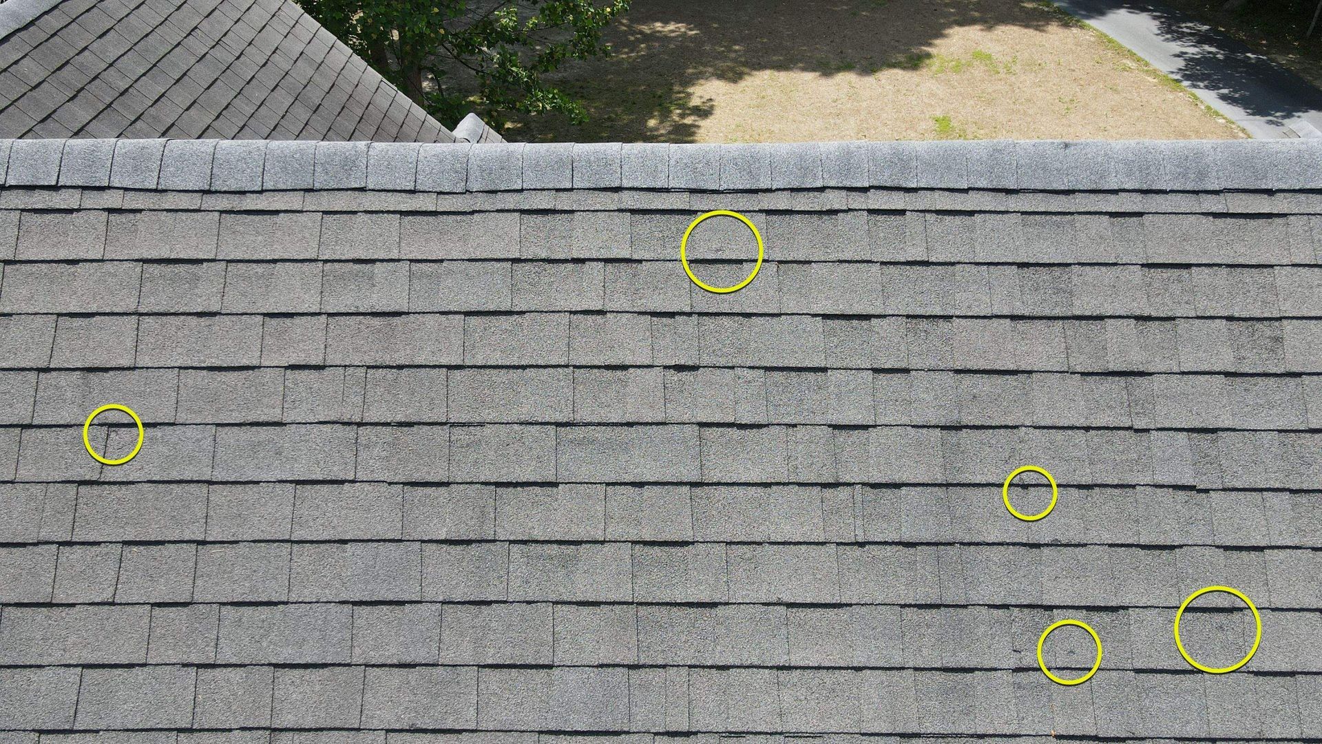 Image of roof during hail damage inspection by RETEX's Mark Erickson, with added yellow circles highlighting damaged areas.
