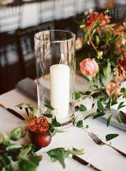 There is a candle in a glass vase on the table.