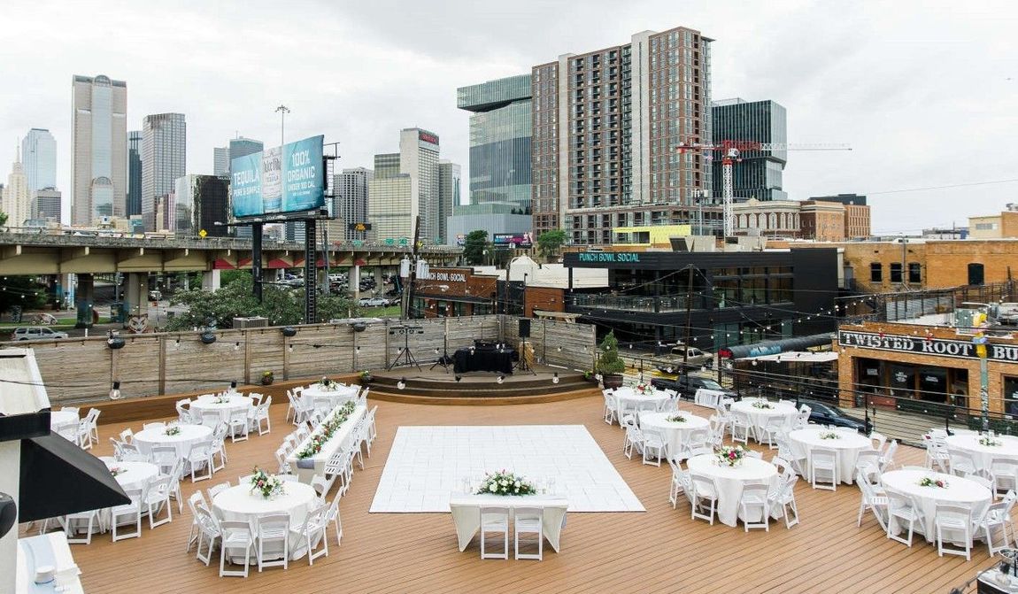 A large white dance floor is surrounded by tables and chairs in front of a city skyline.