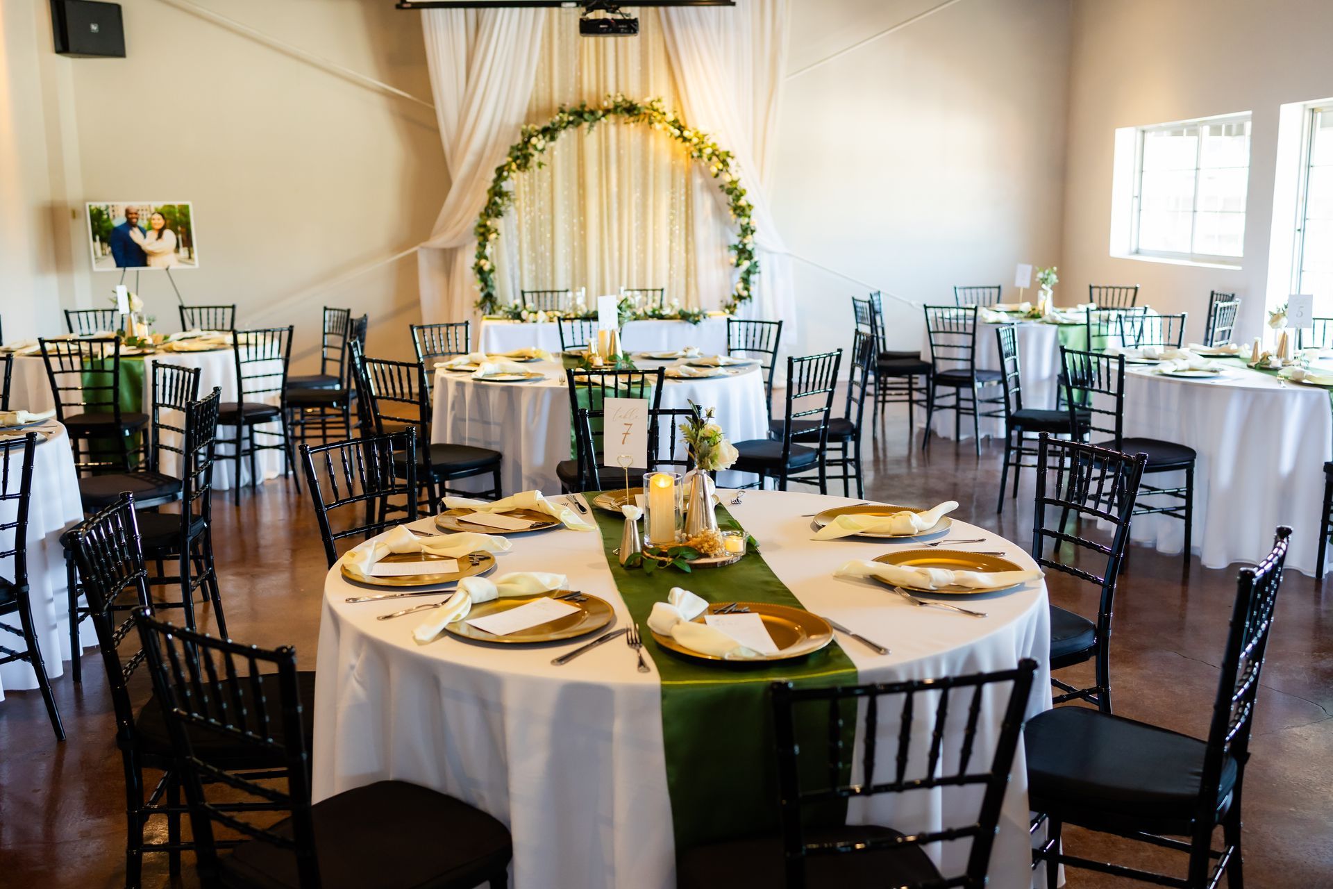 A large room with tables and chairs set up for a wedding reception.