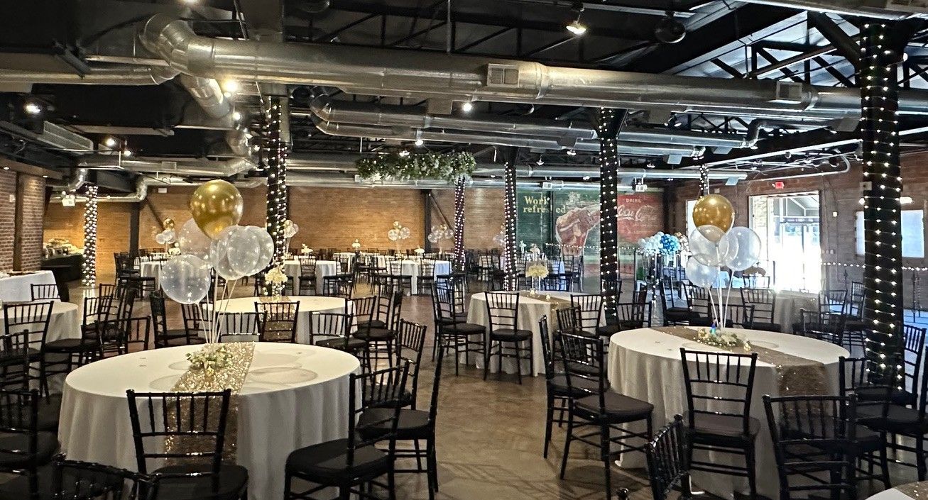 A large room filled with tables and chairs and balloons.