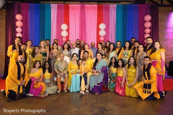 A large group of people are posing for a picture in front of a colorful backdrop.