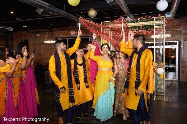 A group of people are standing around a woman in a yellow dress.