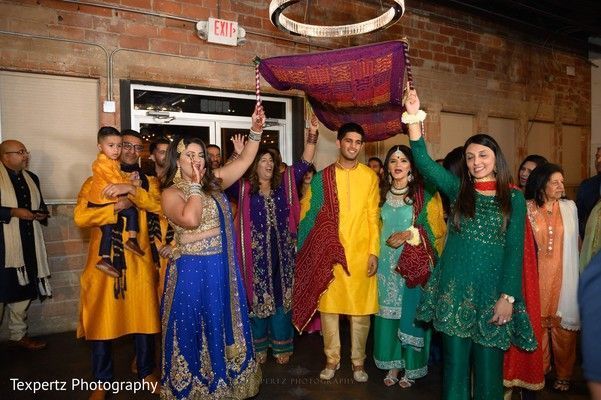 A group of people are standing in a room holding a blanket.