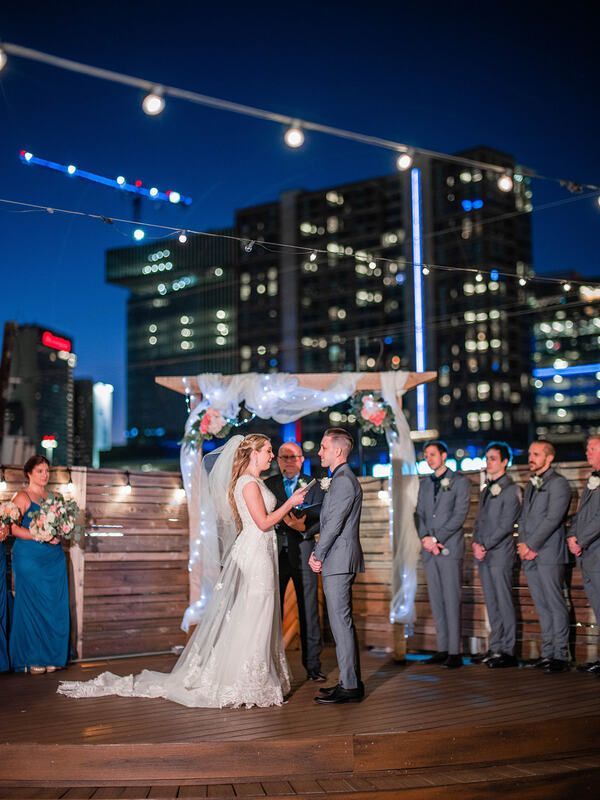 A bride and groom are getting married in front of a city skyline.