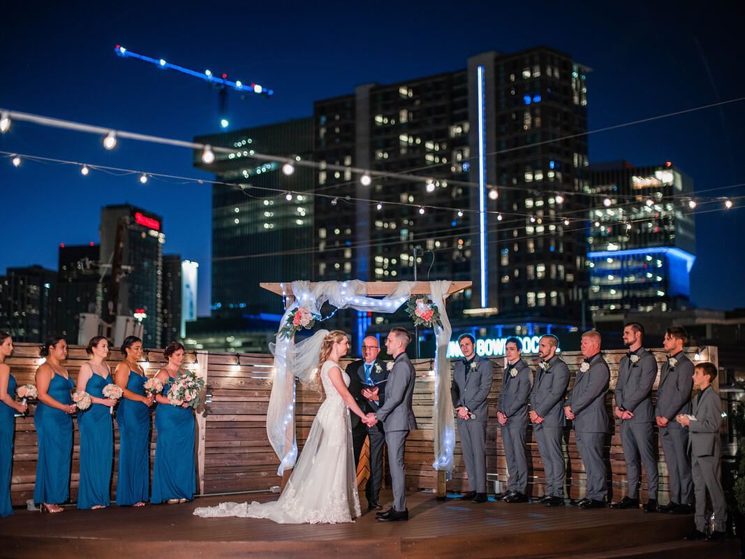 A bride and groom are getting married in front of a city skyline.