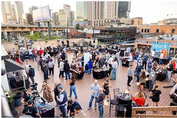 A large group of people are dancing on a rooftop deck.
