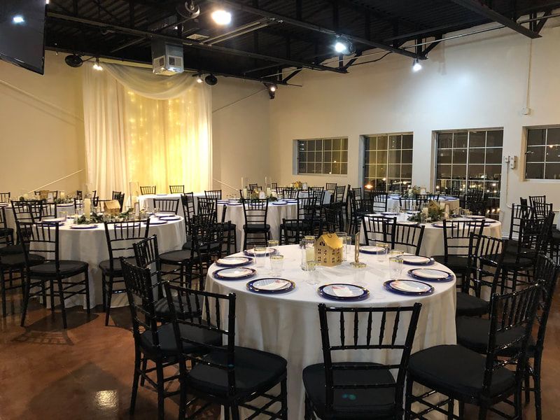 A large room with tables and chairs set up for a wedding reception.