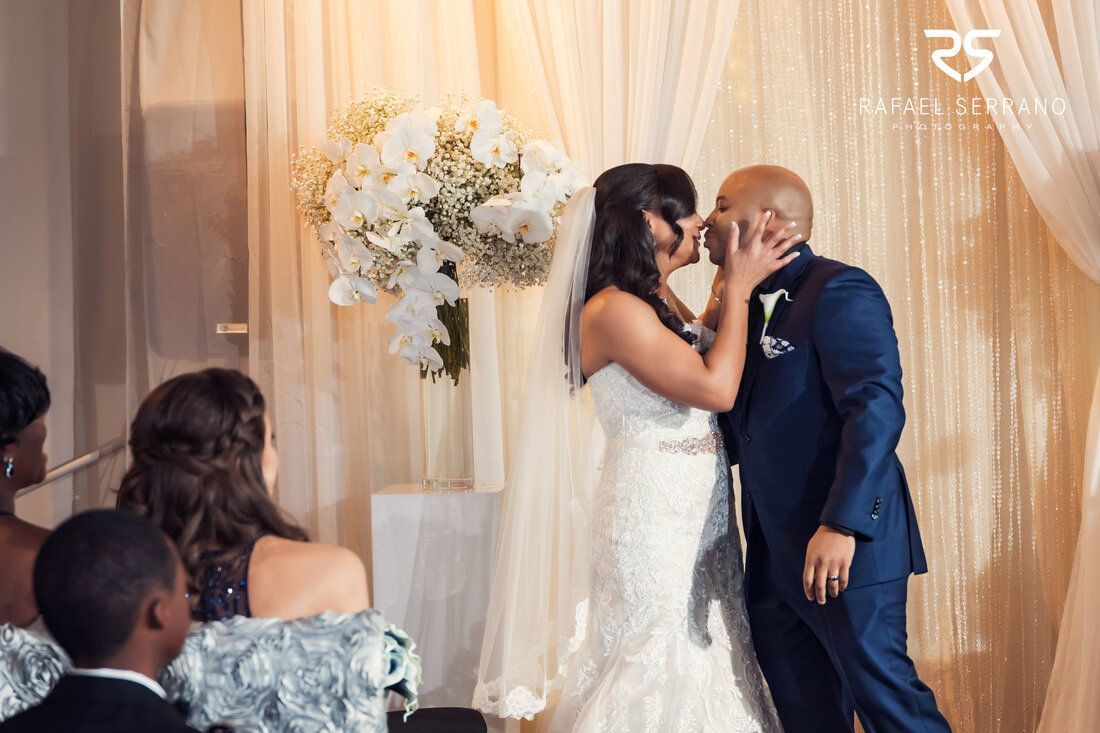 A bride and groom are kissing at their wedding ceremony.