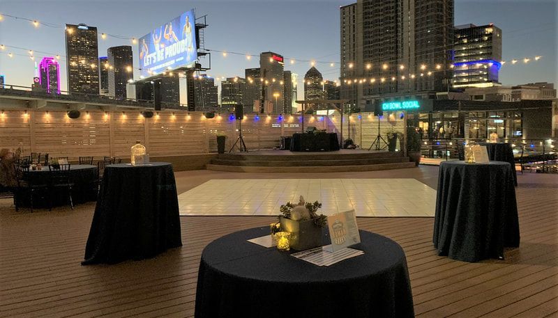 A patio with tables and a dance floor with a city skyline in the background.