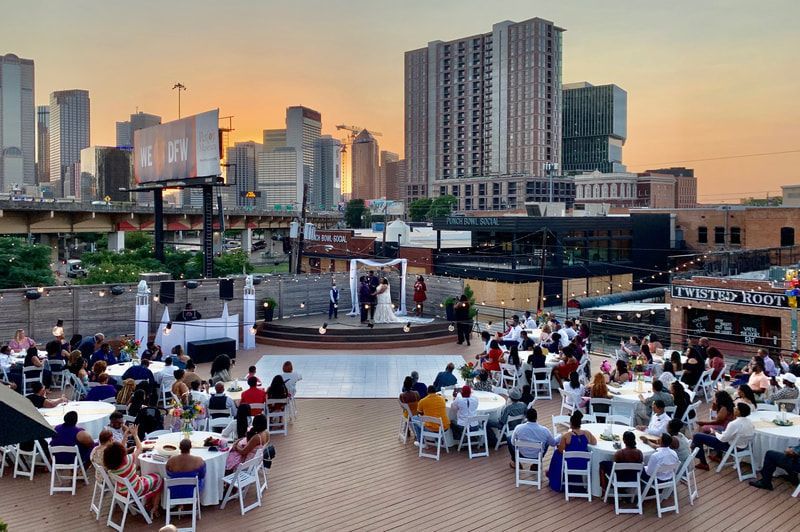 A large group of people are sitting at tables in front of a city skyline.