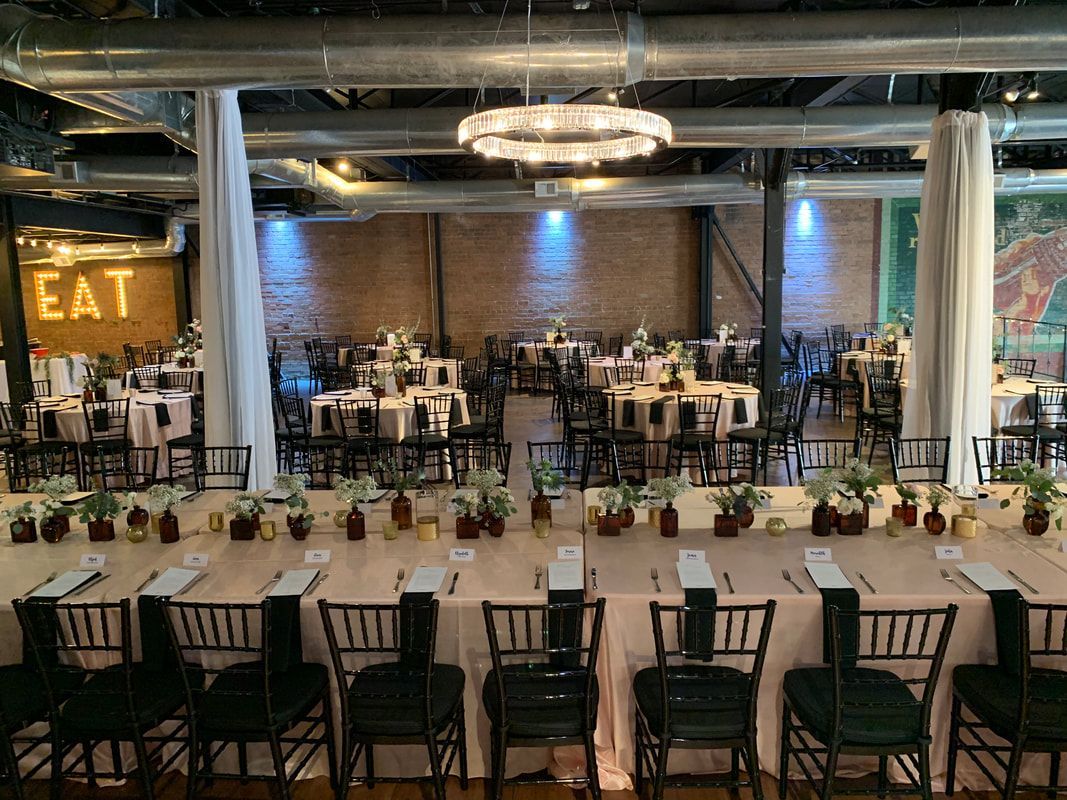 A large room with tables and chairs set up for a wedding reception.