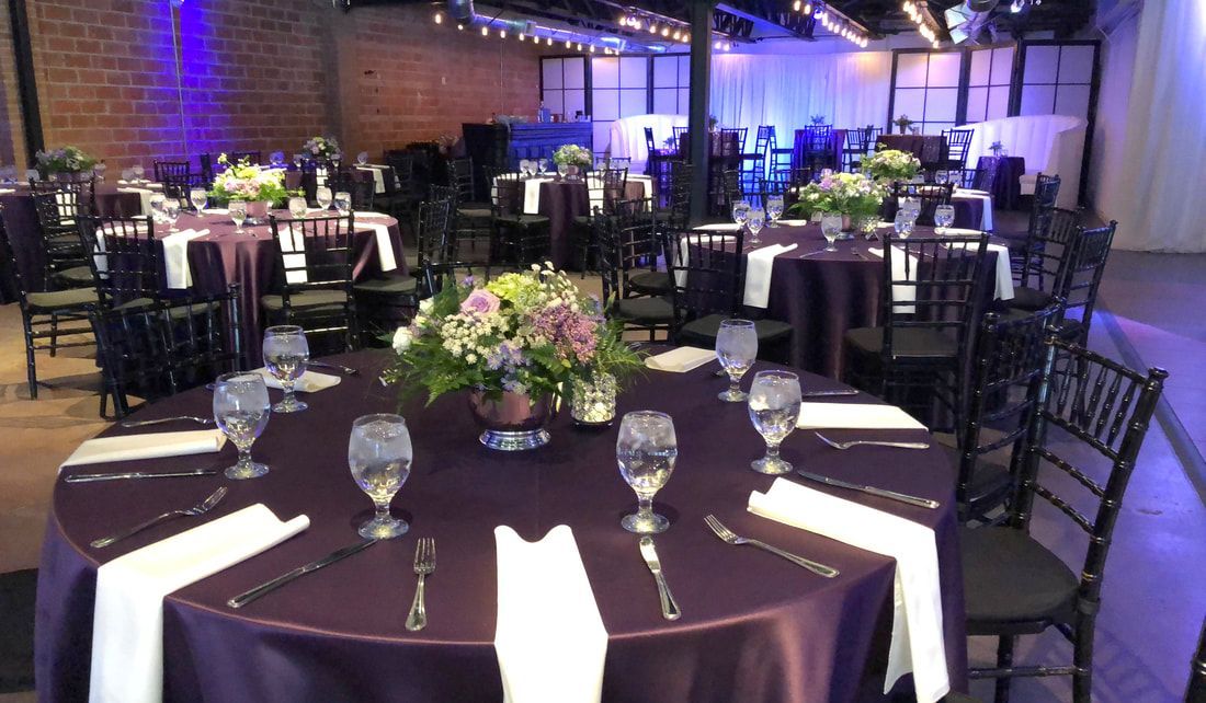 A large room with tables and chairs set up for a wedding reception.