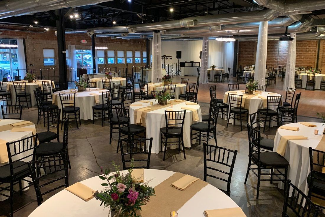 A large room with tables and chairs set up for a wedding reception.