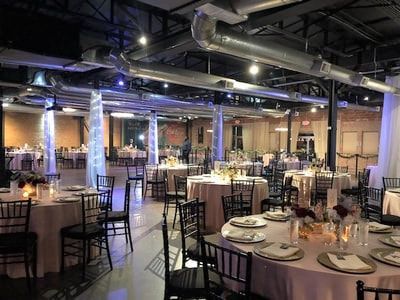 A large room with tables and chairs set up for a wedding reception.