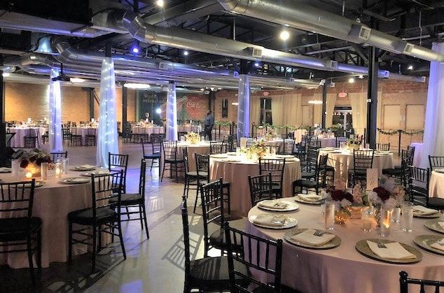 A large room with tables and chairs set up for a wedding reception.