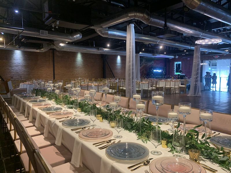 A long table is set for a wedding reception in a large room.