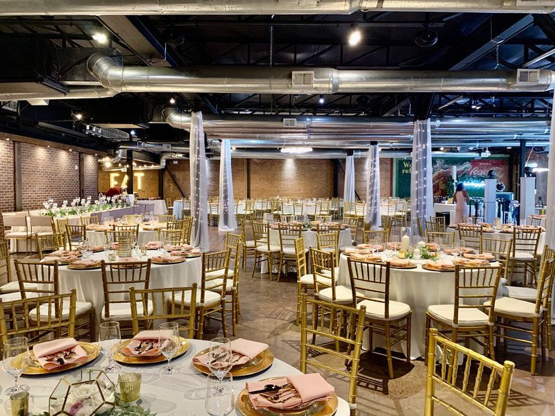 A large room with tables and chairs set up for a wedding reception.