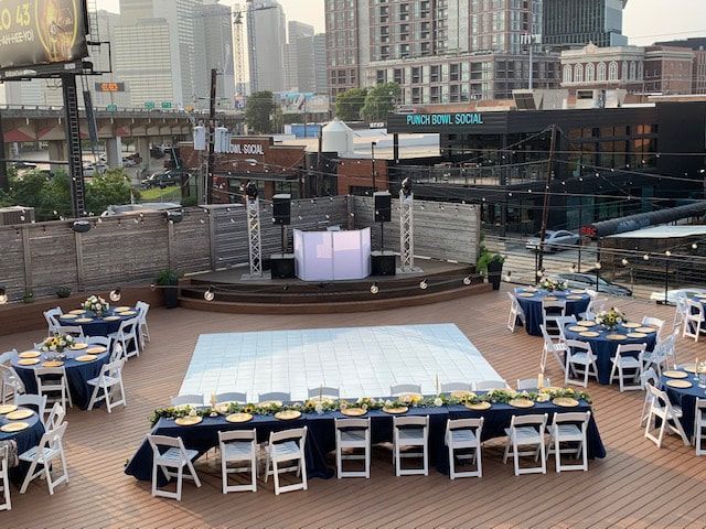 A large white dance floor with tables and chairs in front of it.