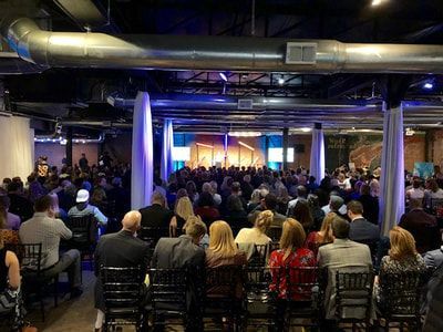 A large group of people are sitting in chairs in a large room.