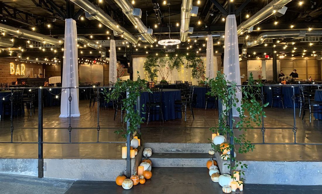 A large room decorated for a wedding with pumpkins and candles.