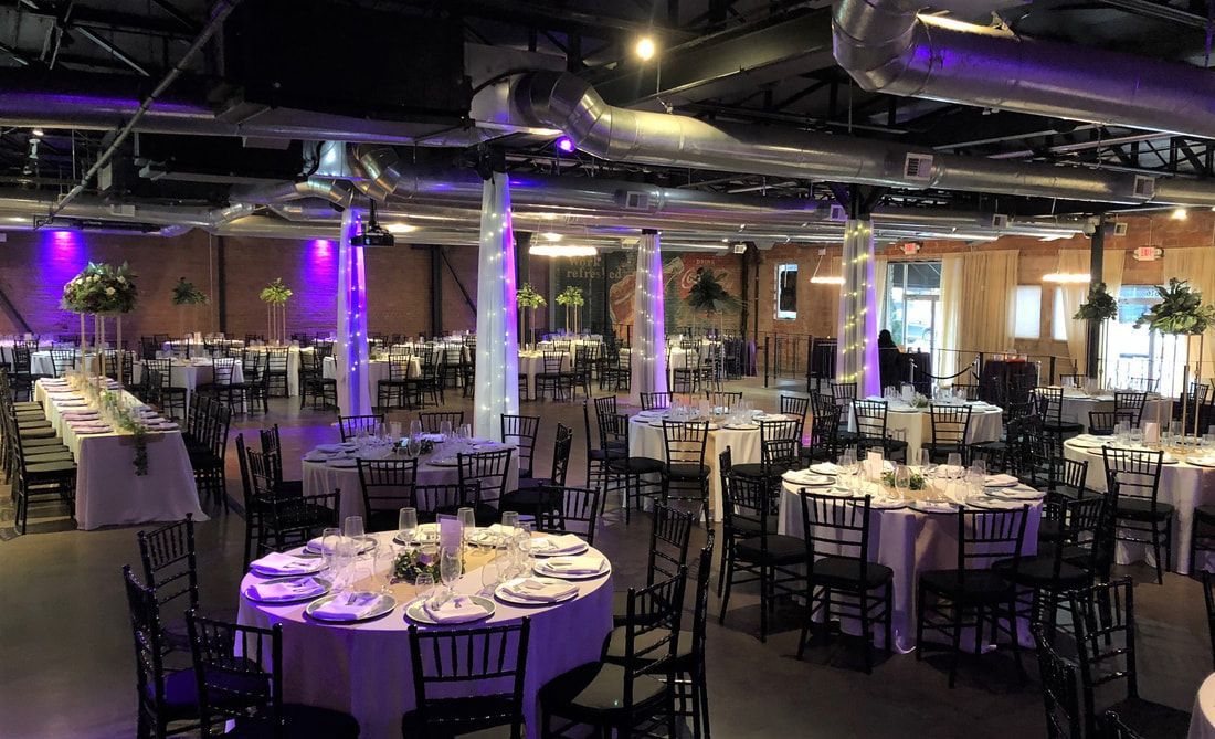 A large room with tables and chairs set up for a wedding reception.