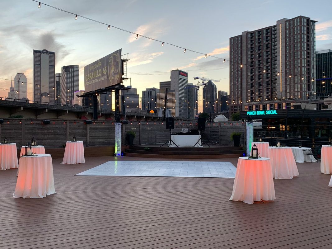 A white dance floor is surrounded by tables and a city skyline in the background.