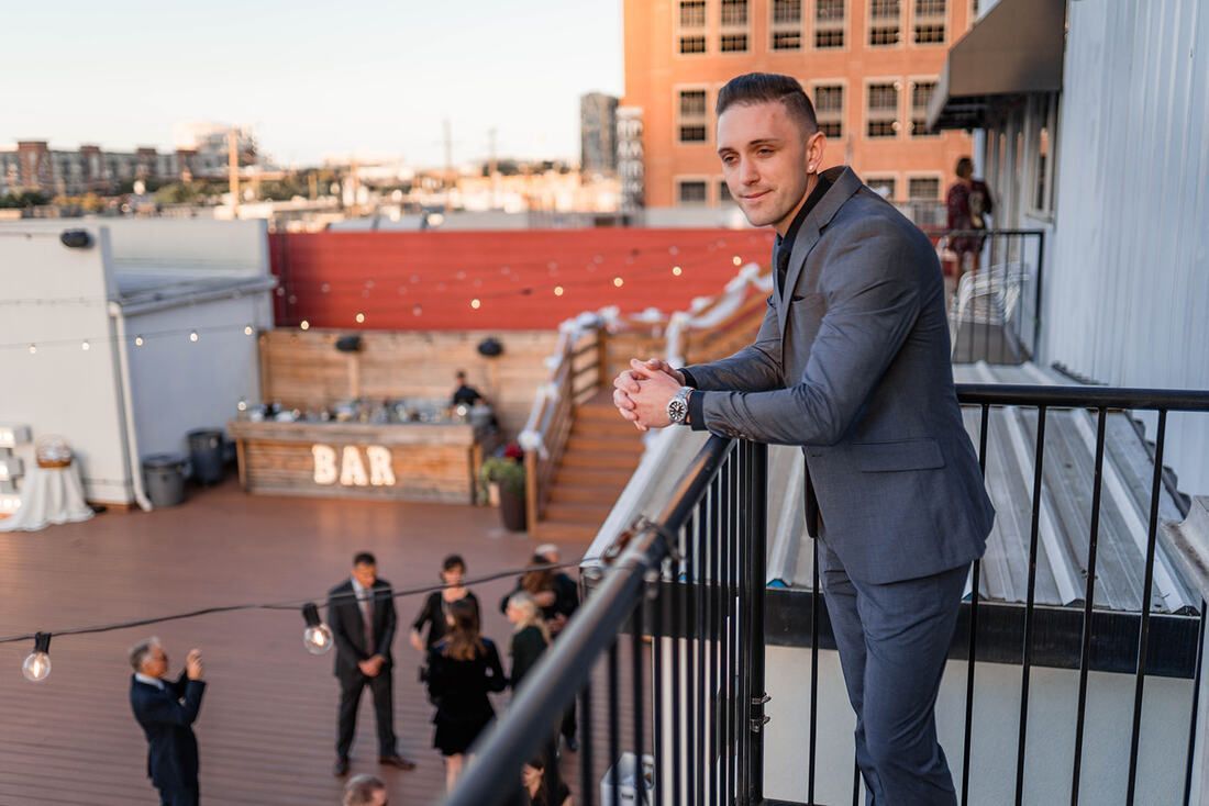 A man in a suit is standing on a balcony overlooking a city.