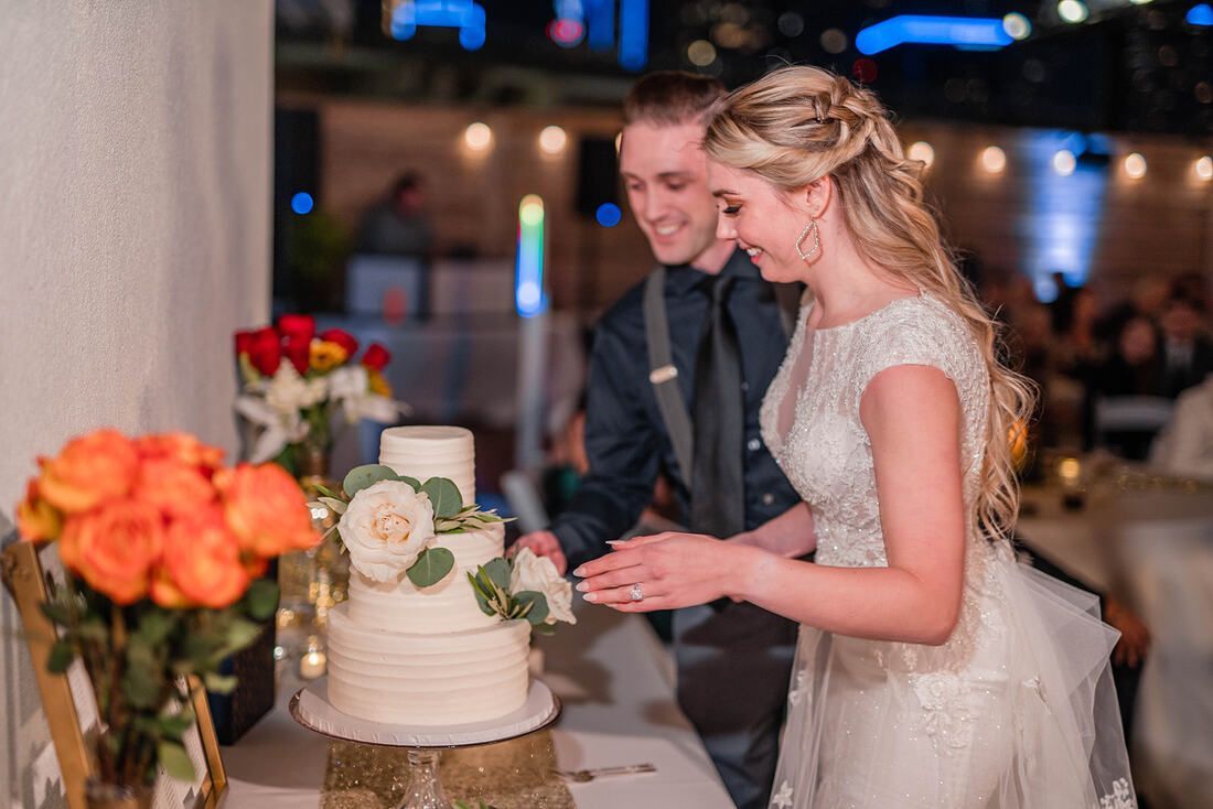 A bride and groom are cutting their wedding cake at their reception.