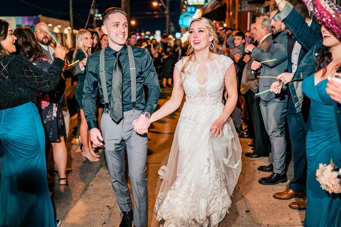 A bride and groom are walking down the street holding hands.