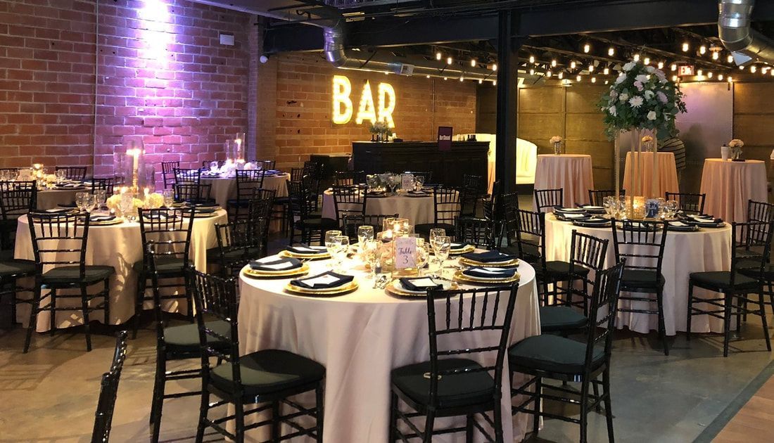 A large room with tables and chairs set up for a wedding reception.