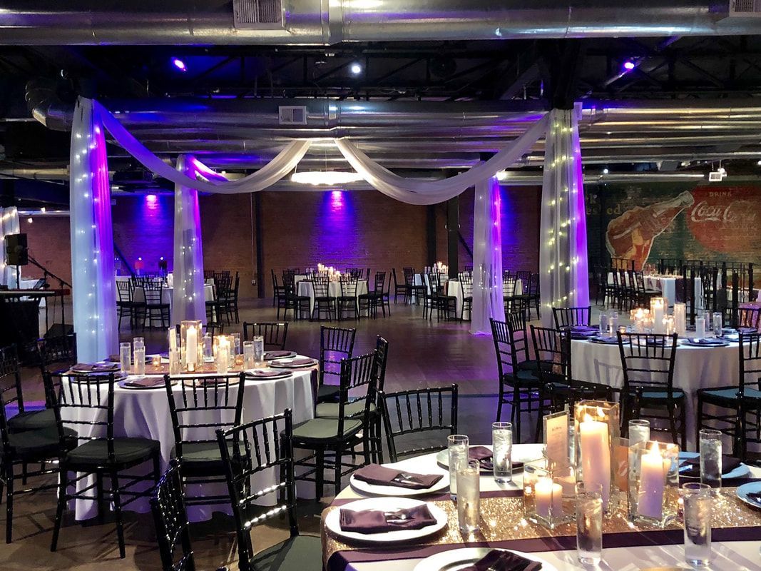 A large room with tables and chairs set up for a wedding reception.