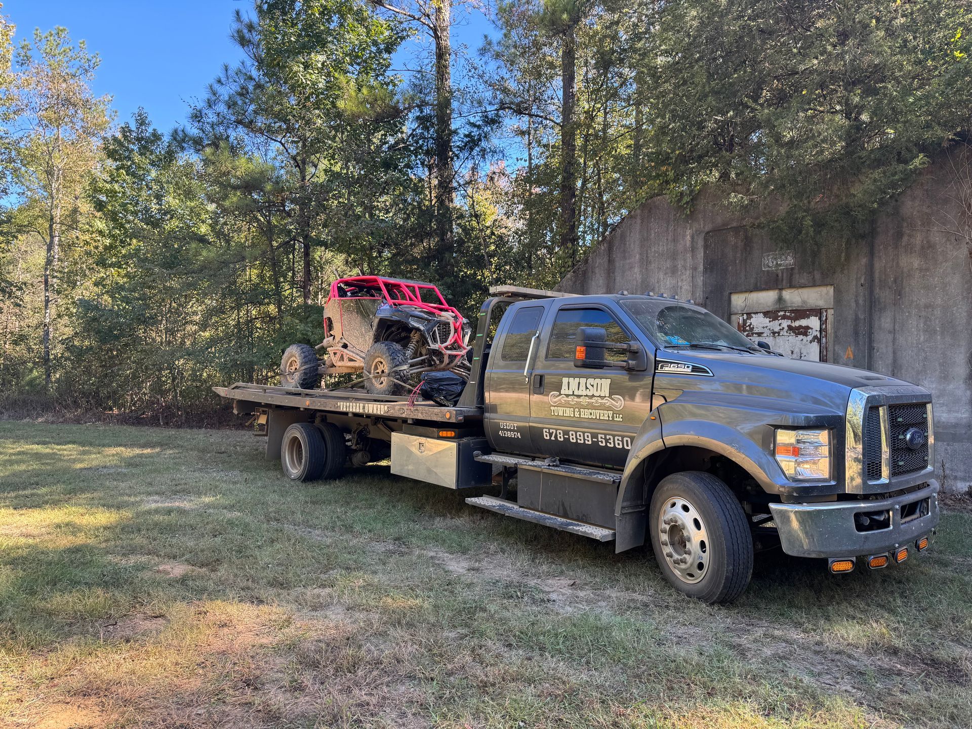 A tow truck is carrying a red atv on the back of it.