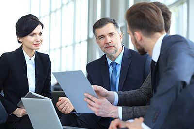 Business people in suits reviewing documents in an office setting.