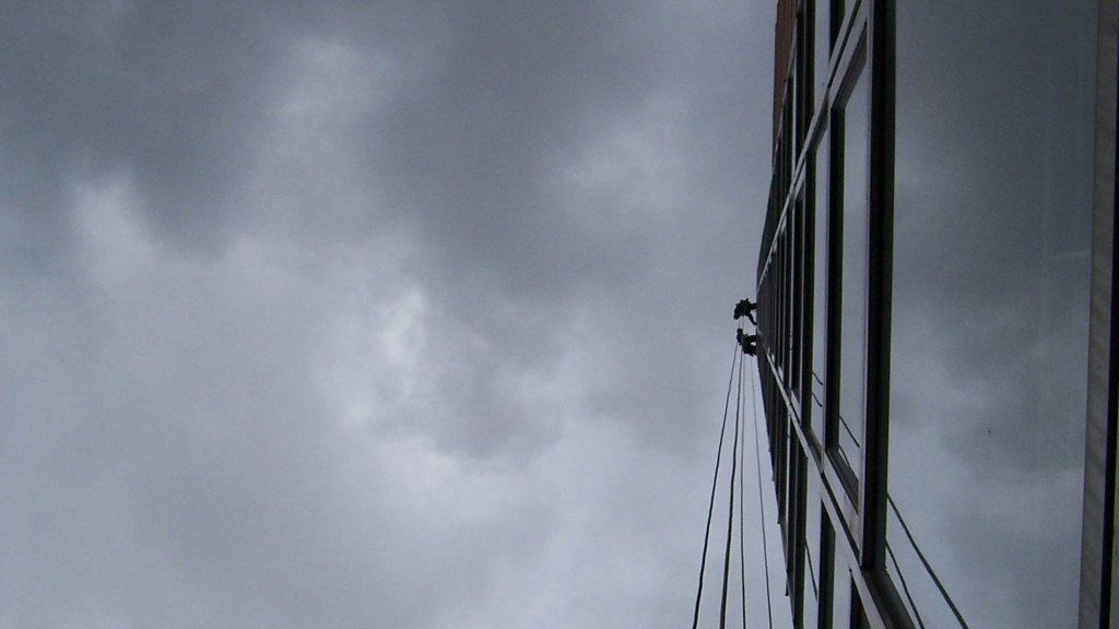 Cielo grigio e nuvoloso sopra il lato di un edificio alto e scuro con finestre riflettenti.
