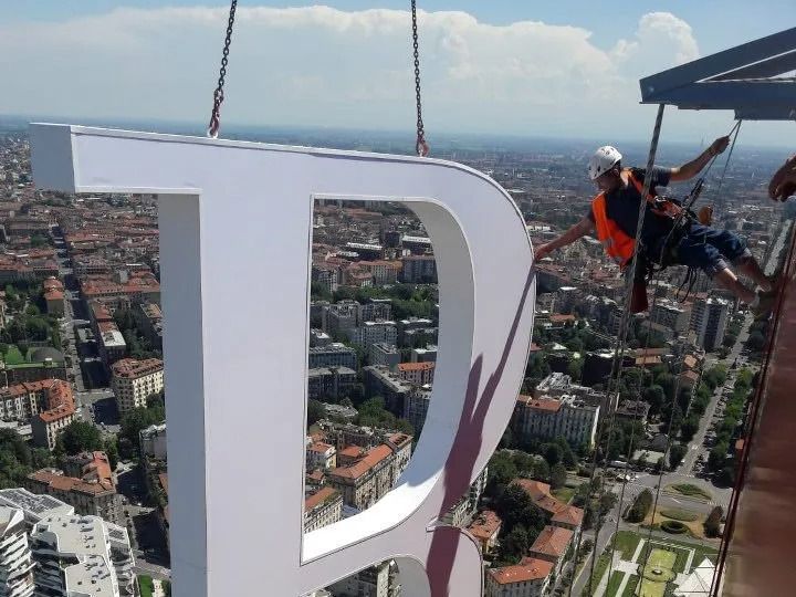 Operai che installano un grande cartello bianco con la 